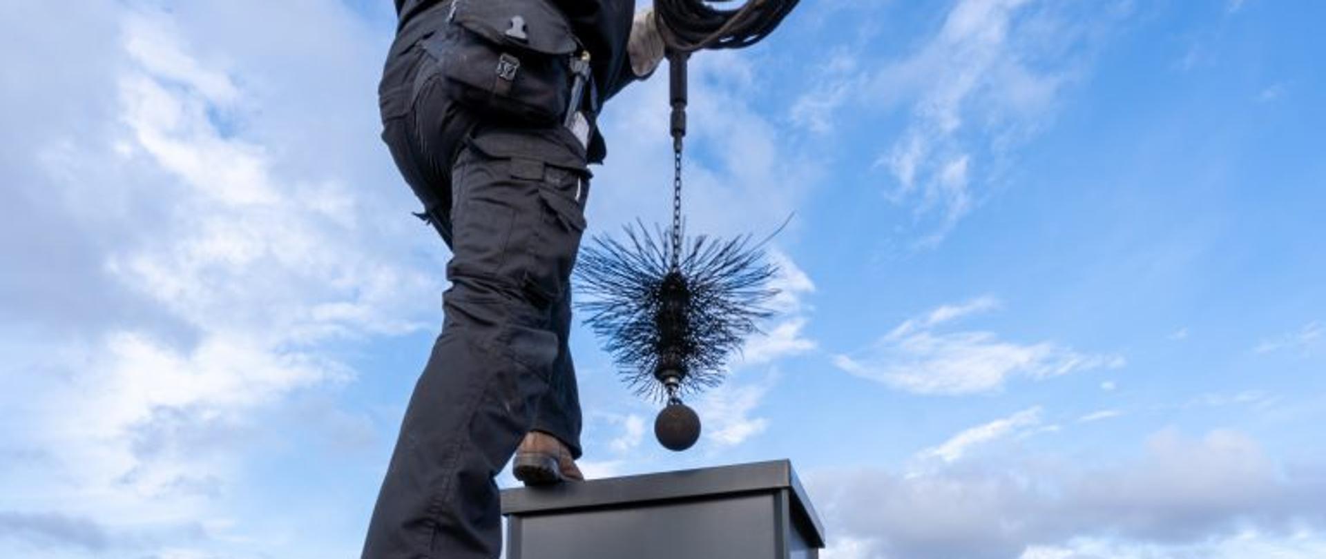 Pan na dachu czyszczący przewód kominowy.