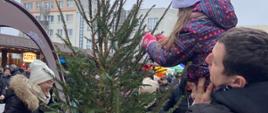 Dzieci z pomocą rodziców ubierają choinkę na Jarmarku