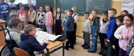 Dzieci stoją przy tablicy w klasie