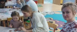 Uczestnicy warsztatów siedzą przy stole, dekorują pierniczki