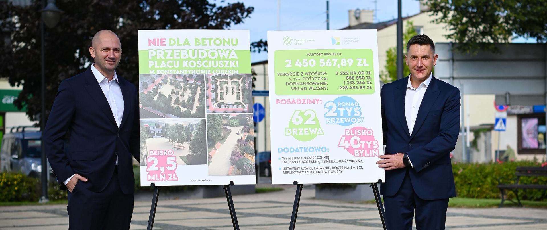 Burmistrzowie w garniturach z planszami na sztalugach na placu w centrum miasta.