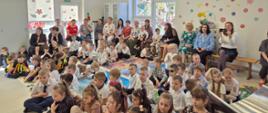 Dzieci, dyrekcja i pracownicy przedszkola oglądają występ artystyczny w wykonaniu dzieci