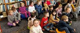 Dzieci w szkolnej bibliotece, siedzą na miękkich pufach