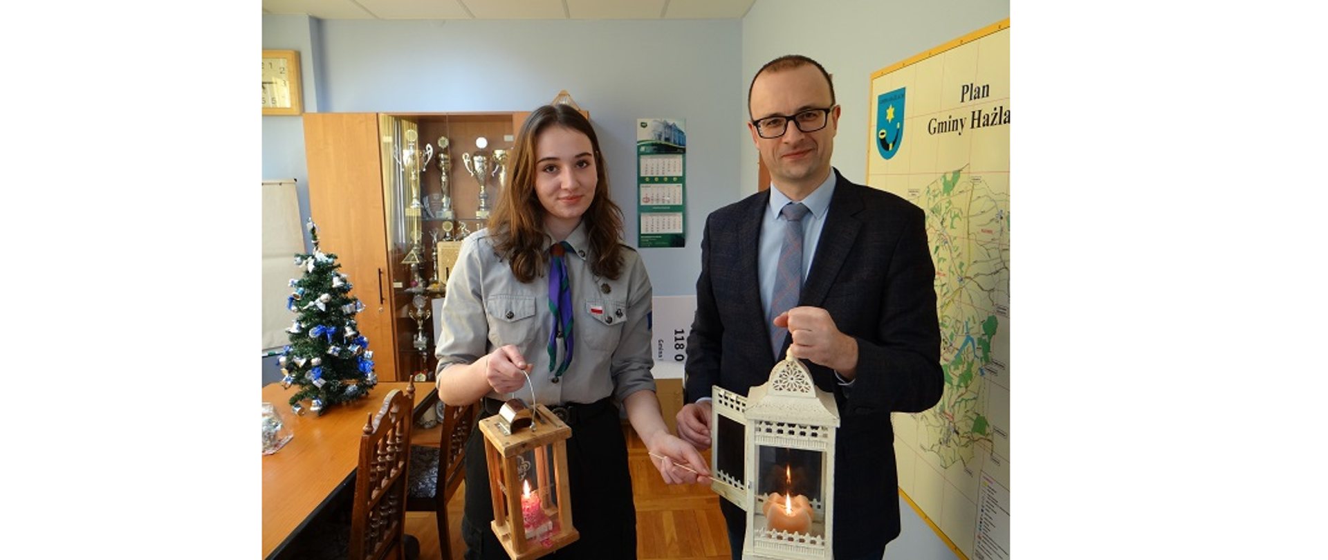 Przekazanie światła w gabinecie Wójta Gminy Hażlach. Na pierwszym planie osoba w harcerskim mundurze i wójt z latarniami. W obu jest już zapalone światło