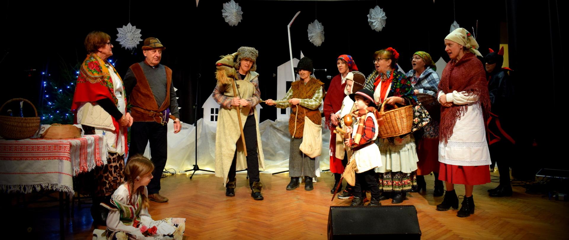 Zdjęcie przedstawia grupę ludzi na scenie w przebraniach podczas Jasełek.