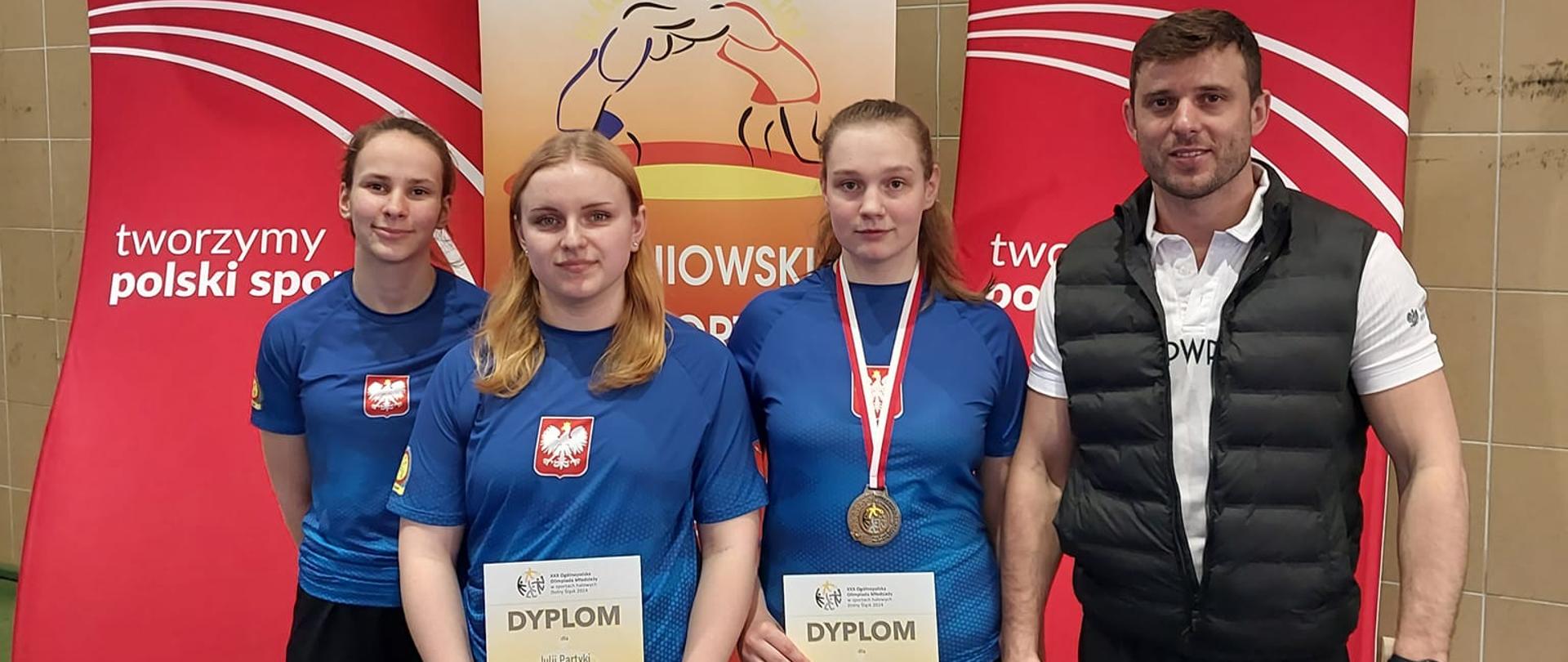Trzyosobowa żeńska reprezentacja Ludowego Uczniowskiego Klubu Sportowego "Suples" w Kraśniku. Od prawej strony stoją: trener Damian Jakóbczyk, Agnieszka Bryczek z dyplomem w ręku i brązowym medalem na szyi, Julia Partyka z dyplom w rękach i Oliwia Torba
