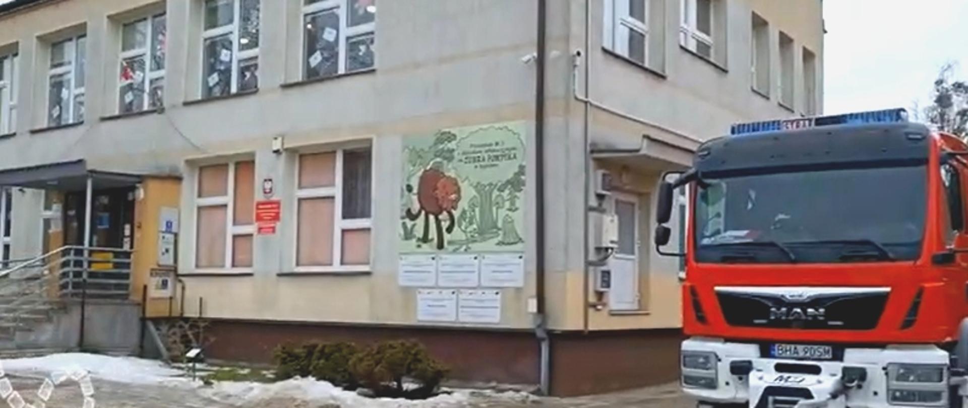 Przy budynku przedszkola stoi wóz strażacki - kadr z filmu