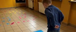Zabawy na korytarzu - uczeń gra w klasy