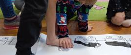 Dzieci w trakcie zabawy - malowanie stóp, które są odbijane na kartkach