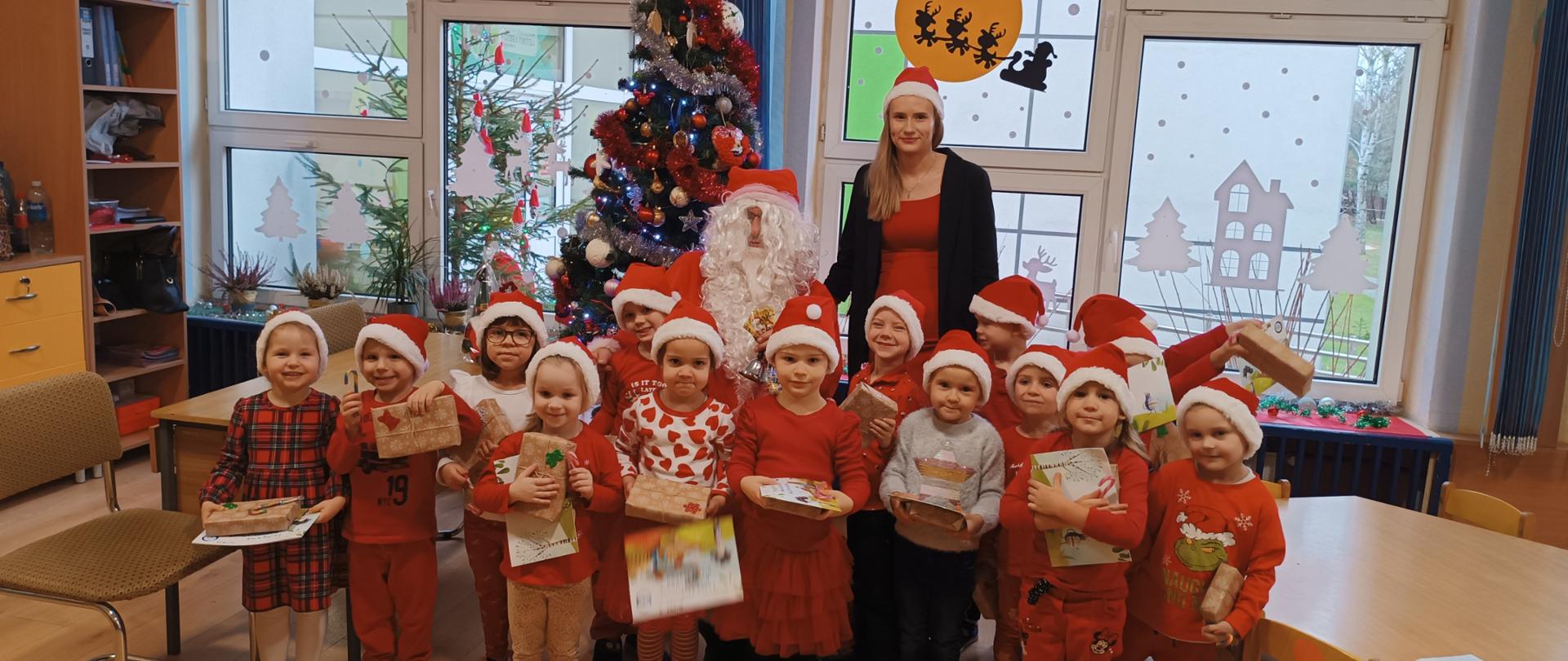 Mikołajki w przedszkolu - dzieci, nauczycielka i mężczyzna przebrany za św. Mikołaja pozują do zdjęć