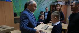 Zdjęcie przedstawia Wicestarostę Kraśnickiego Andrzeja Misztala wręczającego laptop uczniowi IV klasy Szkoły Podstawowej Specjalnej w Kraśniku.