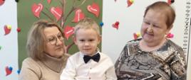 Chłopczyk pozuje do zdjęcia ze swoimi babciami