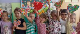 Dzieci pozują do zdjęcia z przygotowanymi sercami
