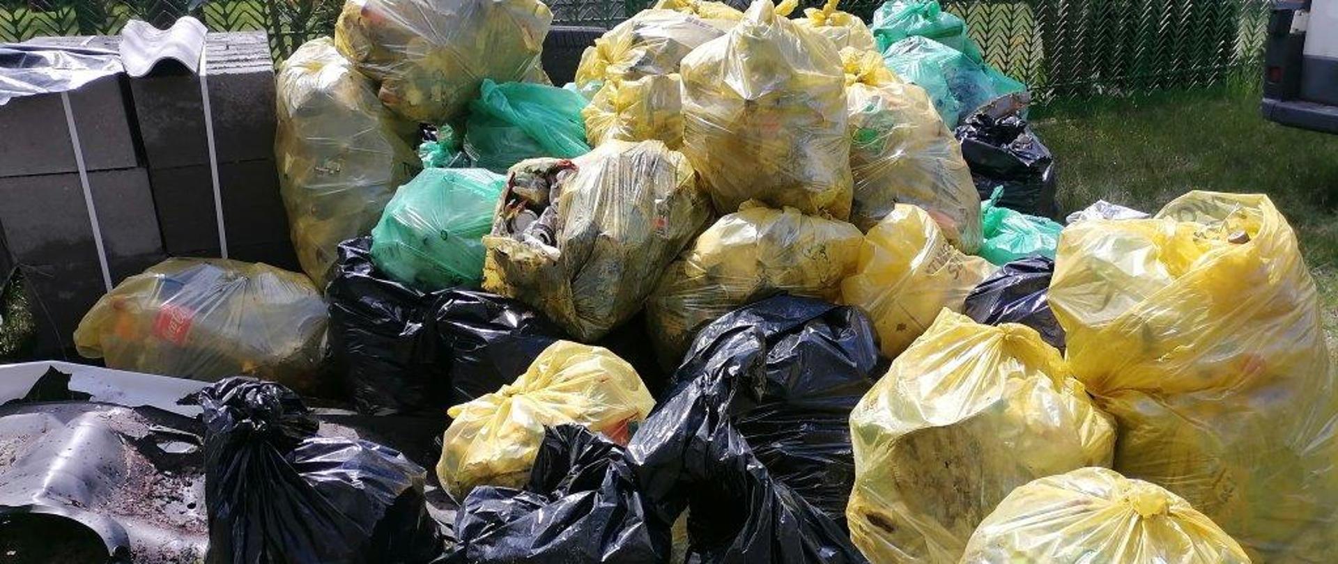 Kilkanaście zółtych i czarnych worków plastikowych leżących w nieładzie