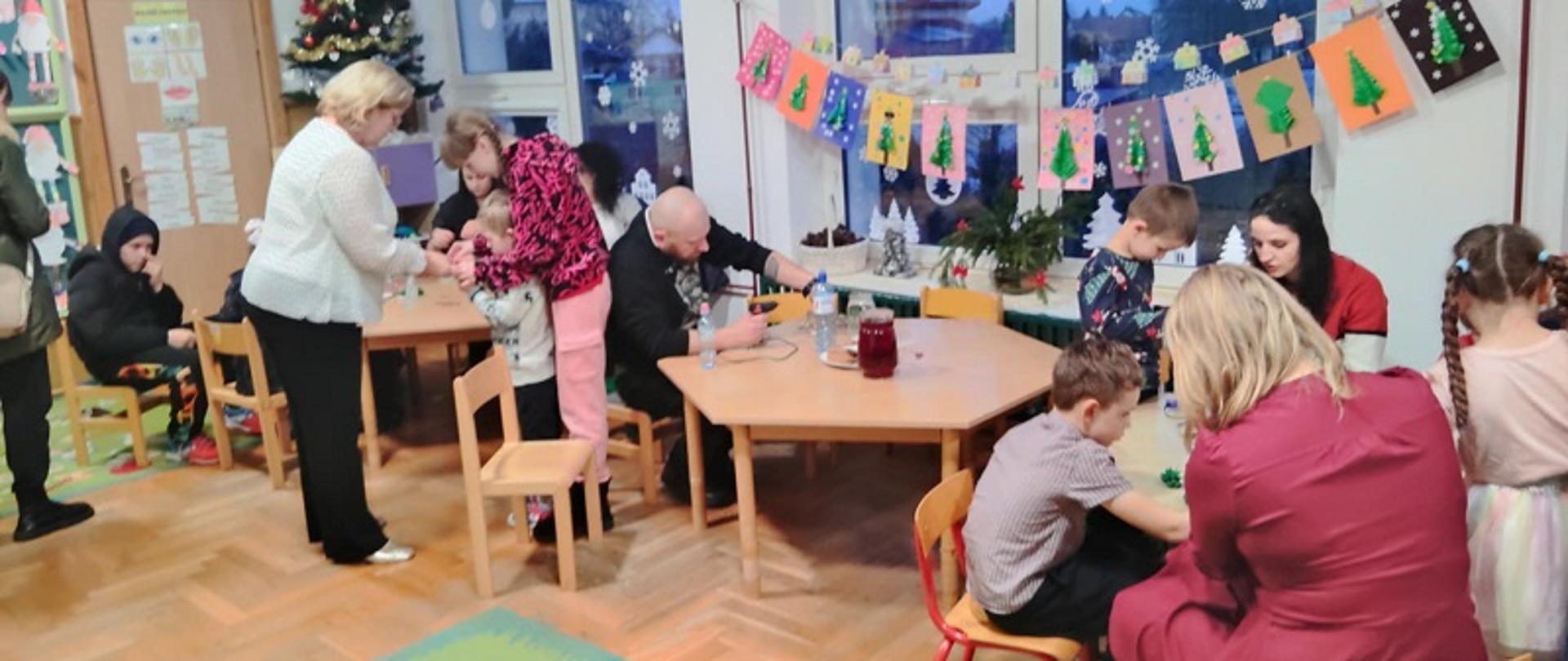 W trakcie warsztatów - przedszkolaki z bliskimi siedzą przy stołach