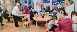 W trakcie warsztatów - przedszkolaki z bliskimi siedzą przy stołach