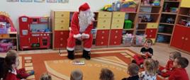 Przed dziećmi siedzi człowiek przebrany za Świętego Mikołaja