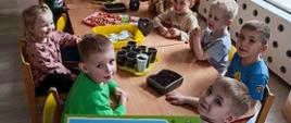 Dzieci pozują do zdjęcia, siedzą przy stole