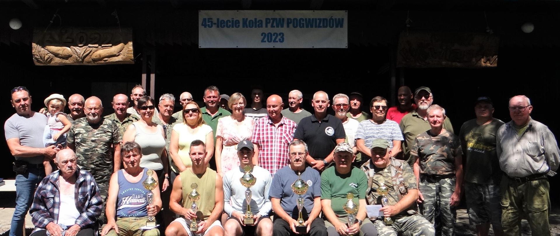 Pamiątkowa fotografia członków Koła PZW w Pogwizdowie. Nad nimi napis: 45-lecie Koła PZW Pogwizdów 2023
