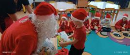 Mikołajki w przedszkolu - Mikołaj rozdaje dzieciom prezenty