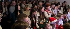 Zebrani goście siedzą na krzesłach w sali remizy.