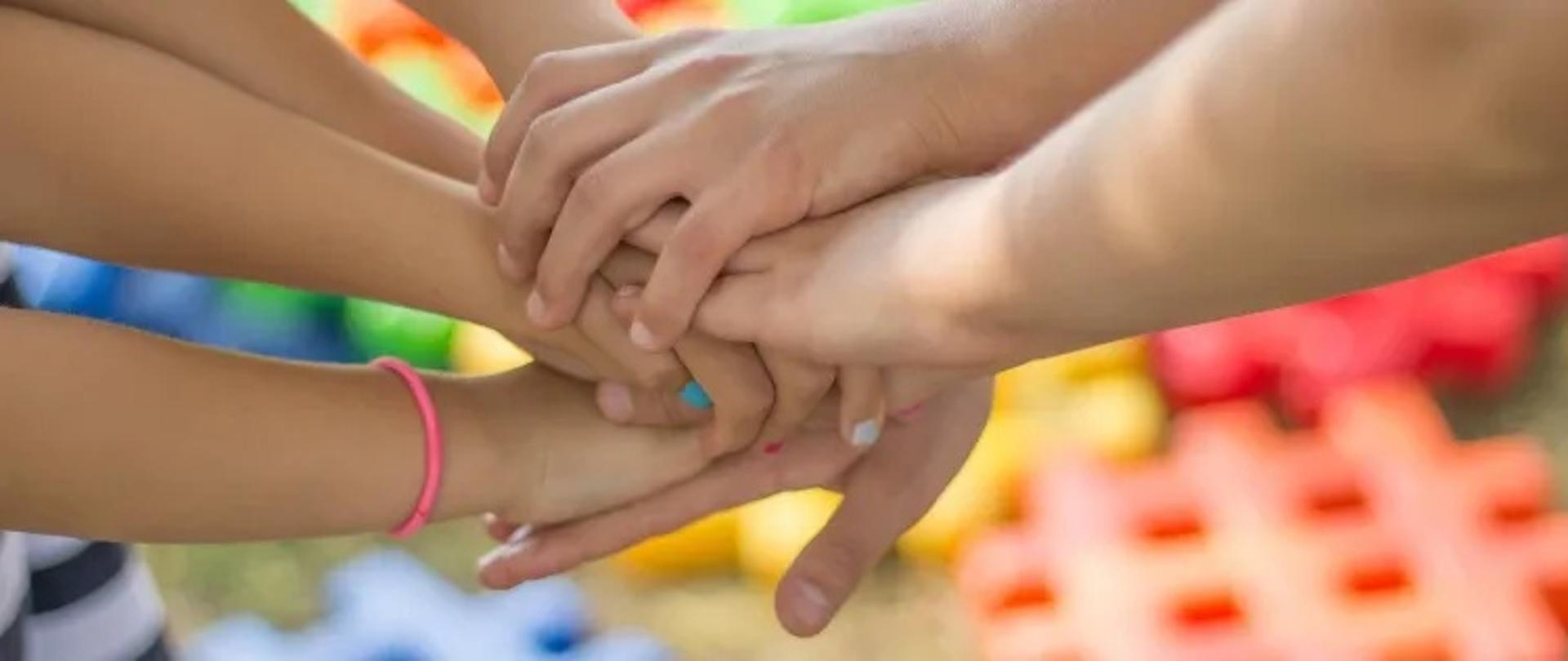 Grupowy uścisk dłoni dziecięcych na kolorowym tle