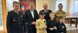 Moment wręczenia nagród uczestnikom. Na zdjęciu od lewej dh. K.Gacek, Wójt T. Rajca, dh R. Wodziak, st. kpt. mgr inż. M. Zając. przed organizatorami stoi troje uczestników 