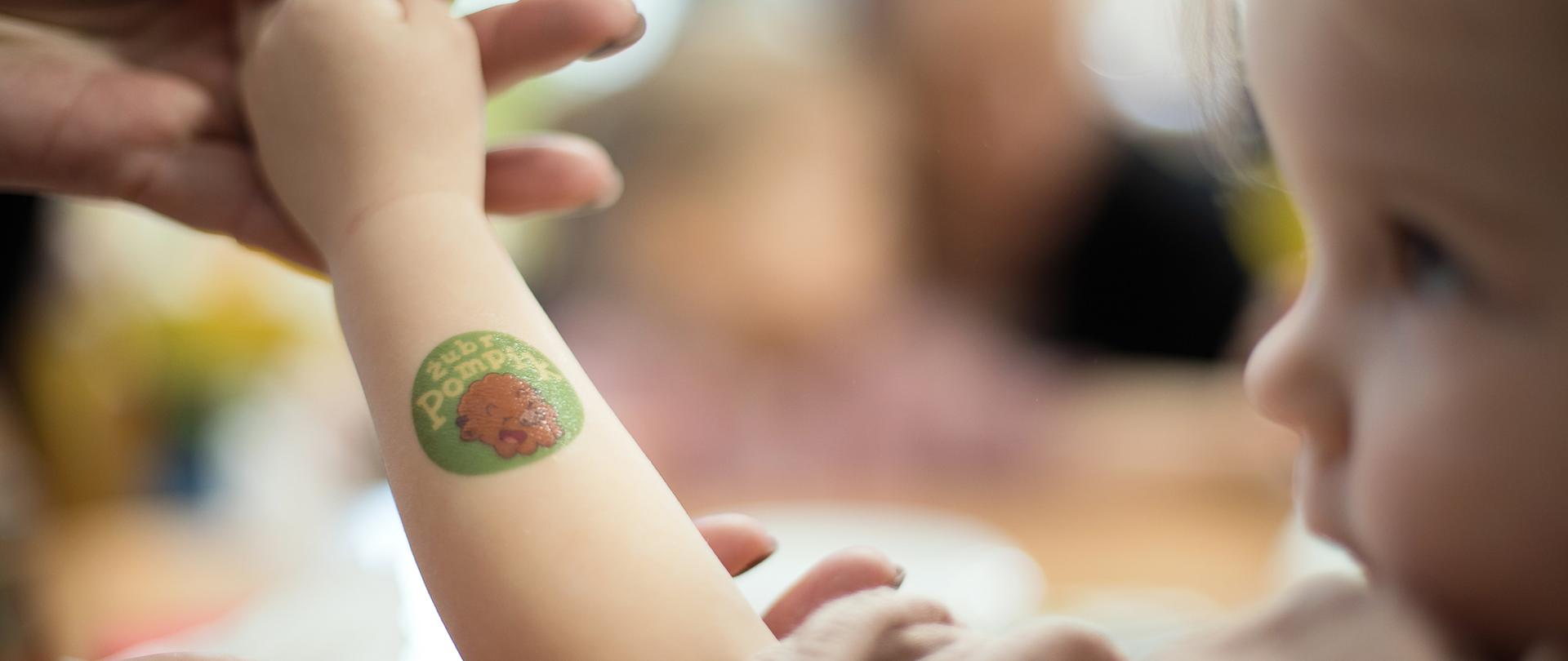 Dziecko prezentuje na rączce tatuaż z logo przedszkola