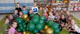 Dzieci pozują do zdjęcia w sali wśród balonów
