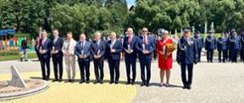Grupa osób stojących na placu podczas oficjalnej części wydarzenia.