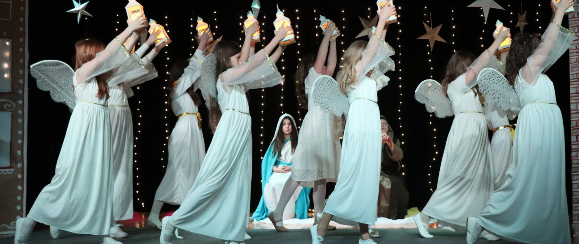 Na zdjęciu znajdują się dzieci przebrane za anioły, w tle dziewczynka przebrana za Maryję. 