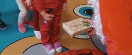 Mężczyzna w przebraniu św. Mikołaja rozmawia z dziećmi, rozdaje im prezenty