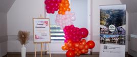 Po prawej baner sołectwa Bielanka, na środku ścianka z kolorowych balonów, po prawej sztaluga z plakatem informującym o dniu kobiet