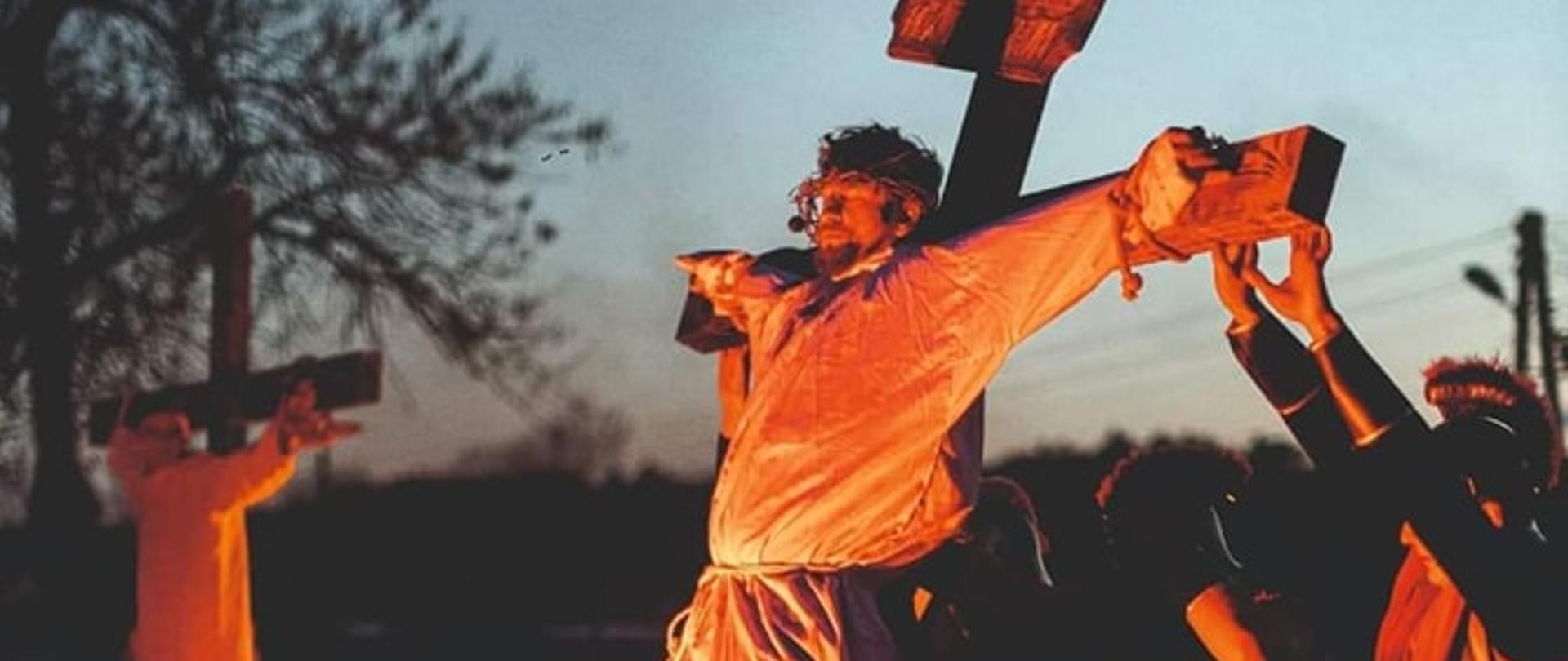 Plakat podzielony jest na trzy części. Górną część stanowi czarny pas z nazwą wydarzenia w kolorze białym: "Misterium Męki Pańskiej w wykonaniu Zespołu Świteź". Środkowa część plakatu to zdjęcie przedstawiające moment podniesienia zawieszonego na krzyżu Chrystusa. W dolnej części znajdują się herby organizatorów wydarzenia: Gminy Trzydnik Duży oraz Powiatu Kraśnickiego oraz data i miejsce wydarzenia: 16 kwietnia 2023 r. o godzinie 19:00, boisko przy budynku OSP w Węglinie.