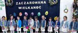 Dzieci wykonują wokalny repertuar na tle ścianki z napisem "Zaczarowana Wielkanoc"