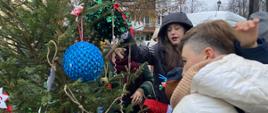 Dzieci z pomocą rodziców ubierają choinkę na Jarmarku