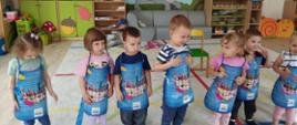 Dzieci w sali zajęć, pozują w fartuchach