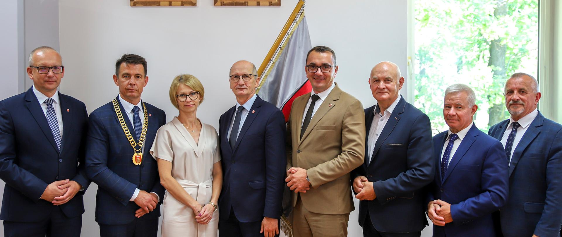 Pamiątkowe zdjęcie członków prezydium Rady Powiatu oraz Zarządu Powiatu na tle sztandaru Powiatu Kraśnickiego.