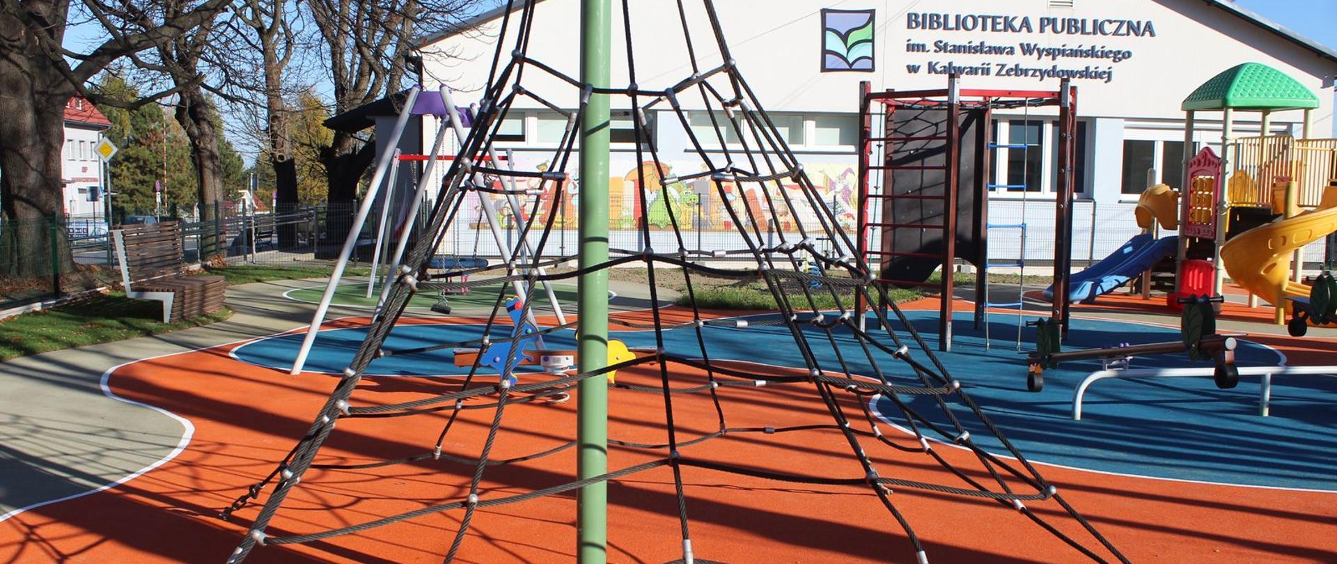 Plac zabaw, na pierwszym planie liniarium, w głębi zjeżdżalnia i huśtawka 