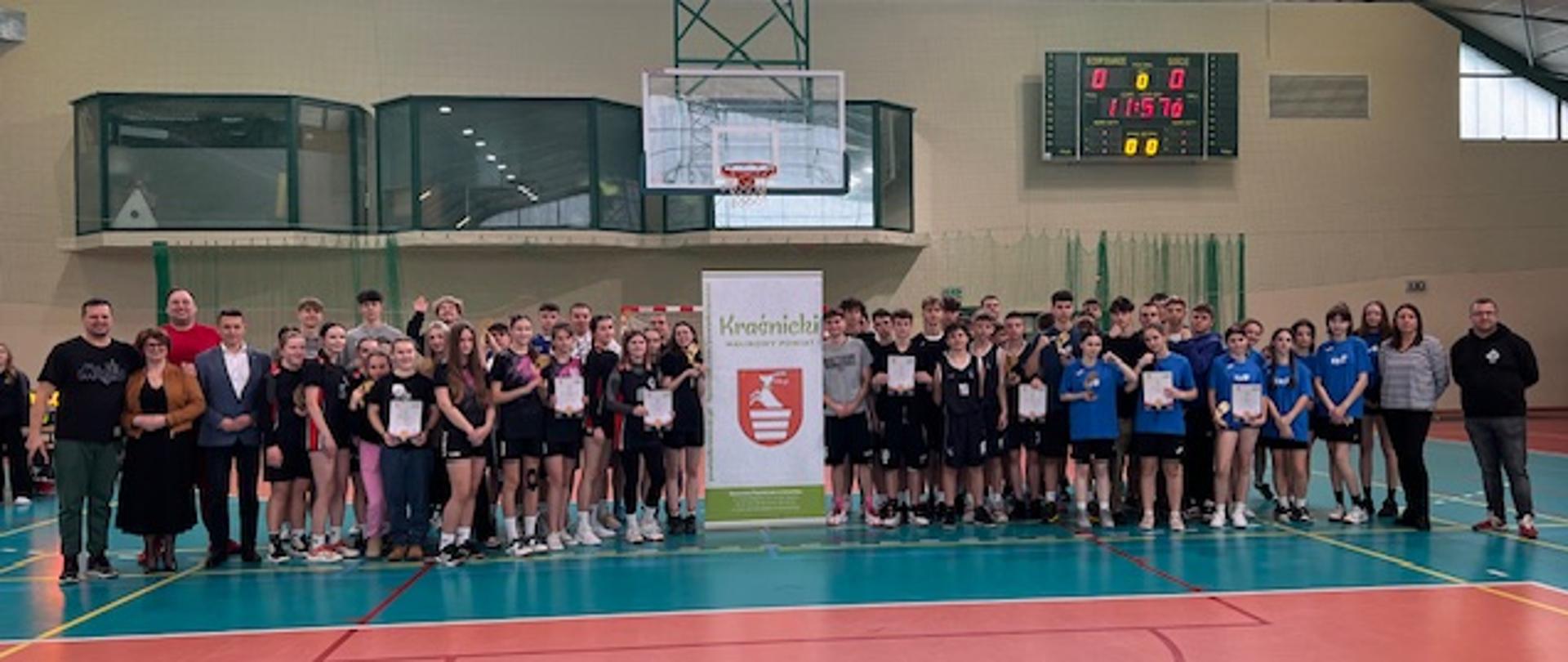 Uczestnicy turnieju stojący wspólnie na hali sportowej