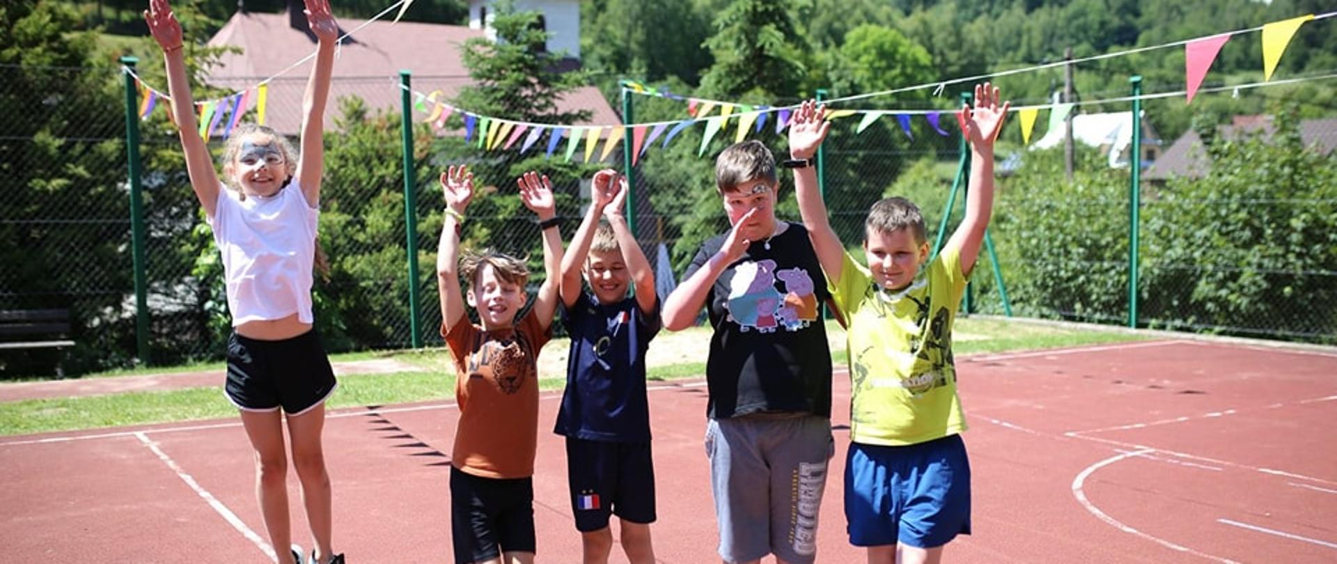 Zdjęcie przedstawia dzieci na boisku przed szkołą pozujące do zdjęcia na pikniku rodzinnym