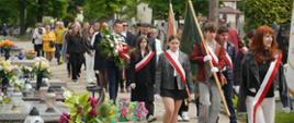 Poczty sztandarowe, młodzież i mieszkańcy przechodzą alejką cmentarza podczas uroczystości upamiętniającej ofiary niemieckiego obozu w Konstantynowie Łódzkim.