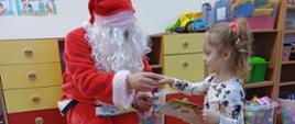 Człowiek przebrany za Świętego Mikołaja wręcza dziewczynce prezent