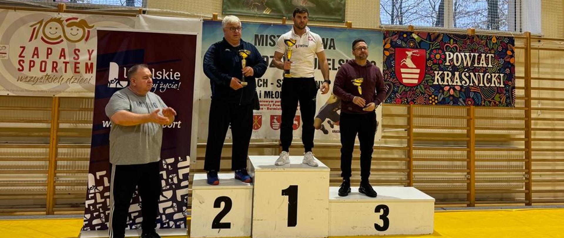 Trenerzy klubowi na podium klasyfikacji drużynowej wraz z pucharami w rękach. Na najwyższym stopniu stoi trener LUKS "Suples" w Kraśniku Damian Jakóbczyk