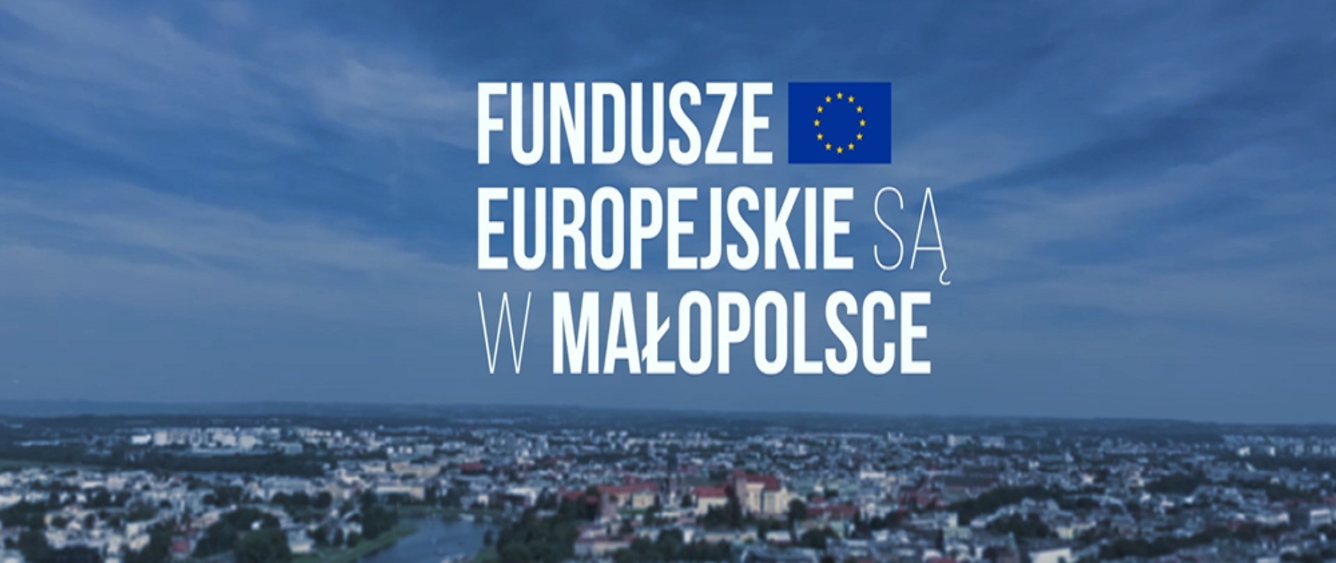 Baner projektu fundusze europejskie są w Małopolsce . Fotografia miasta z góry, większość powierzchni zajmuje niebo z napisem na środku dolna część fotografii to miasto, budynki, zieleń, rzeka. 