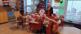 Mikołajki w przedszkolu - dzieci, nauczycielka i mężczyzna przebrany za św. Mikołaja pozują do zdjęć