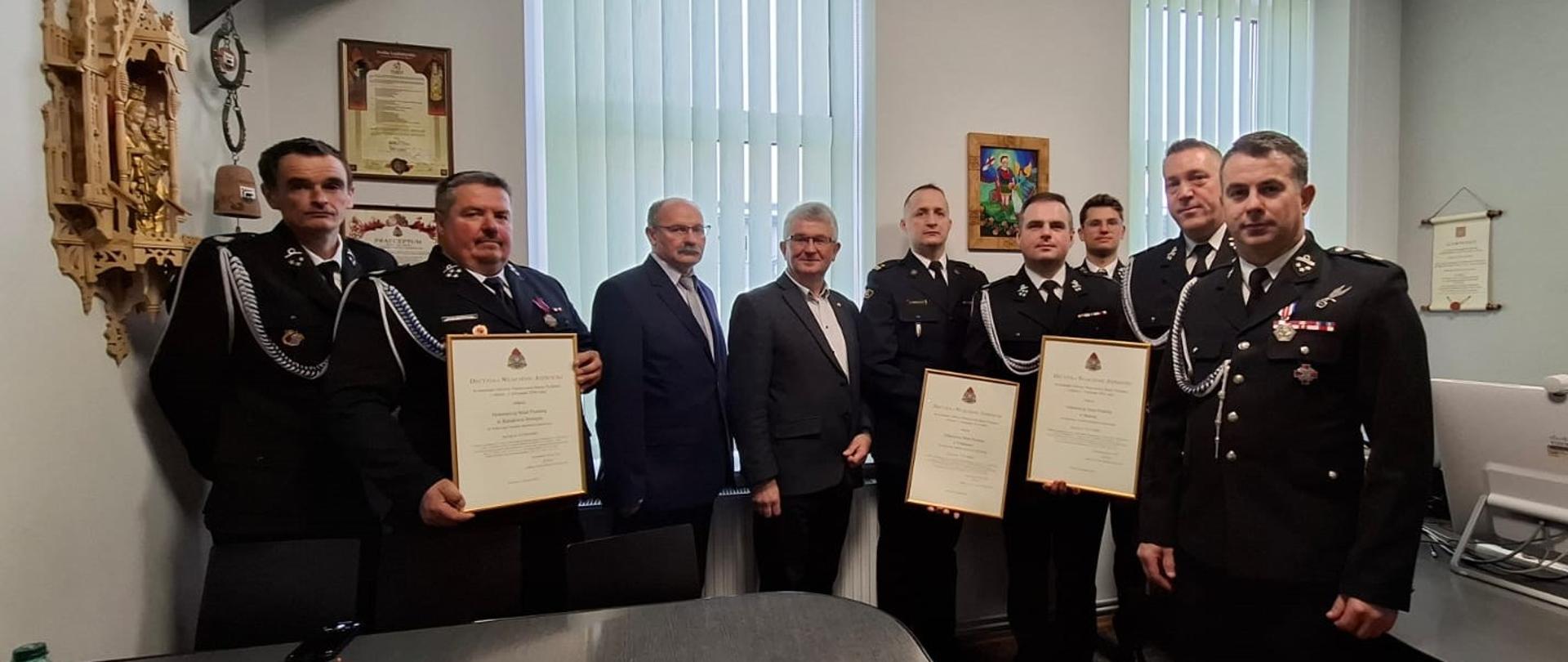 Przedstawiciele jednostek Ochotniczej Straży Pożarnej z Podsarnia oraz ze Skawy trzymają decyzję w sprawie włączenia do krajowego systemu ratowniczo – gaśniczego oraz zaproszeni goście.