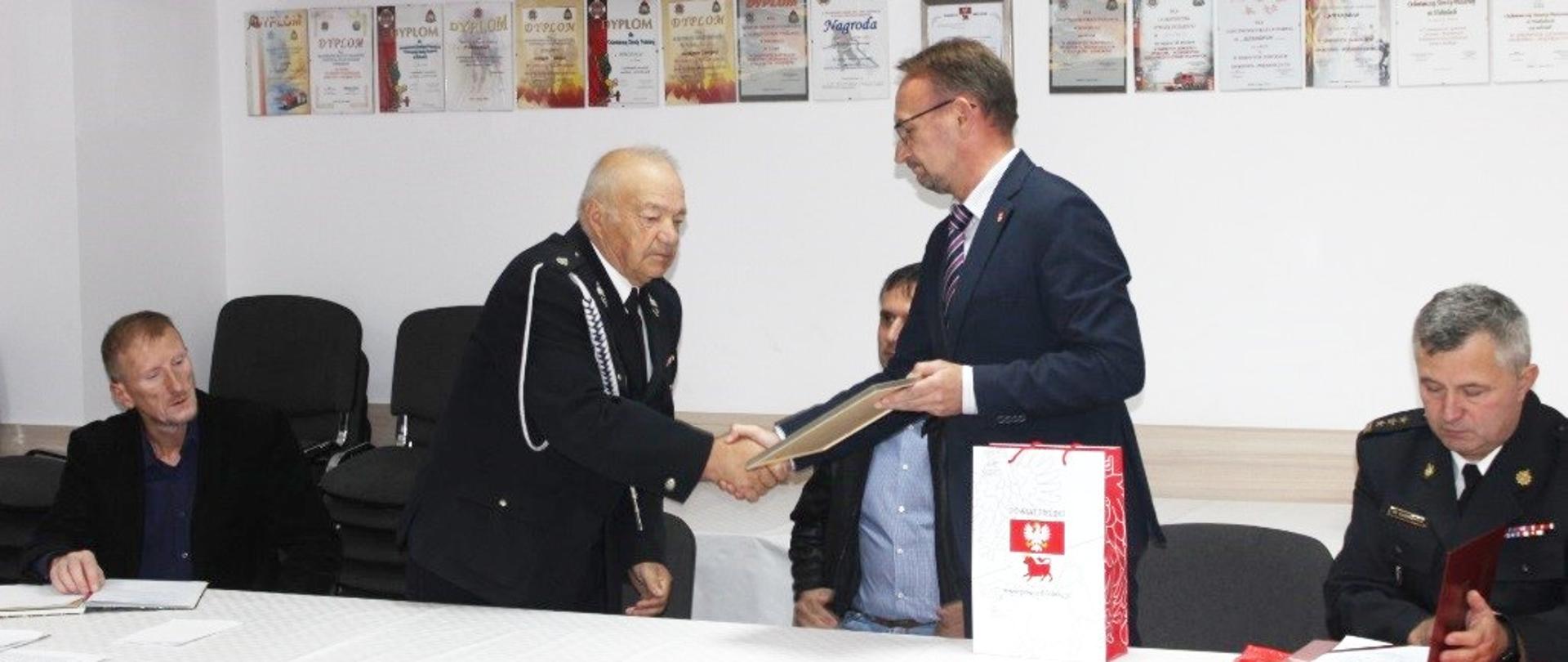 Wicestarosta Piotr Bożko wręcza list gratulacyjny ustępującemu prezesowi OSP Hołody Michałowi Piotrowskiemu