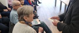 Zastępca Wójta Gminy Raba Wyżna Mieczysław Kurek z opłatkiem w ręce, składa życzenia siedzącym seniorom