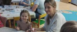 Uczestnicy warsztatów siedzą przy stole, dekorują pierniczki